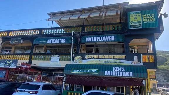 Ken’s Wildflower two-storey bar with green Wray & Nephew awnings and branded signs