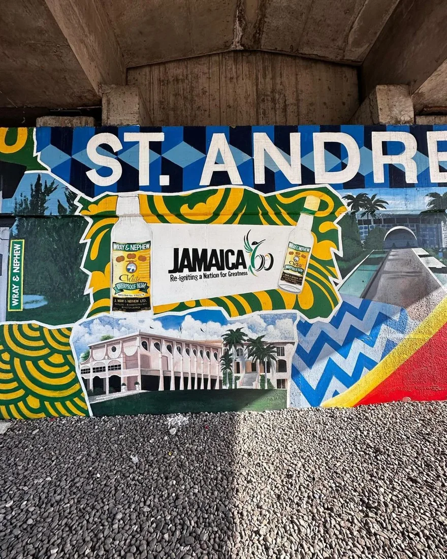 St. Andrew mural beneath an overpass, with Wray & Nephew bottles, landmark buildings and green, yellow and blue patterns
